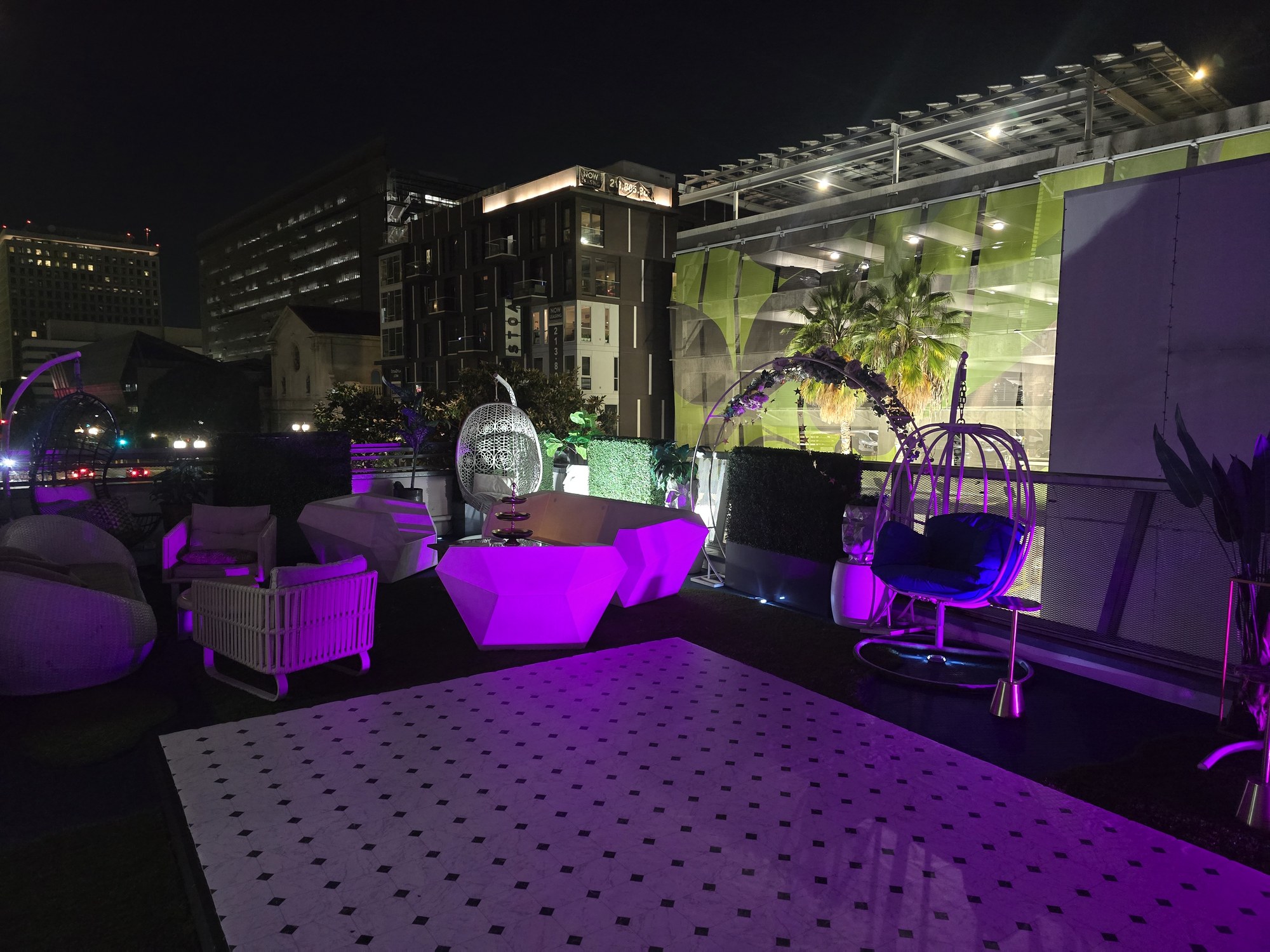 Rooftop lounge at The Kult LA lit in purple at night with the DTLA skyline