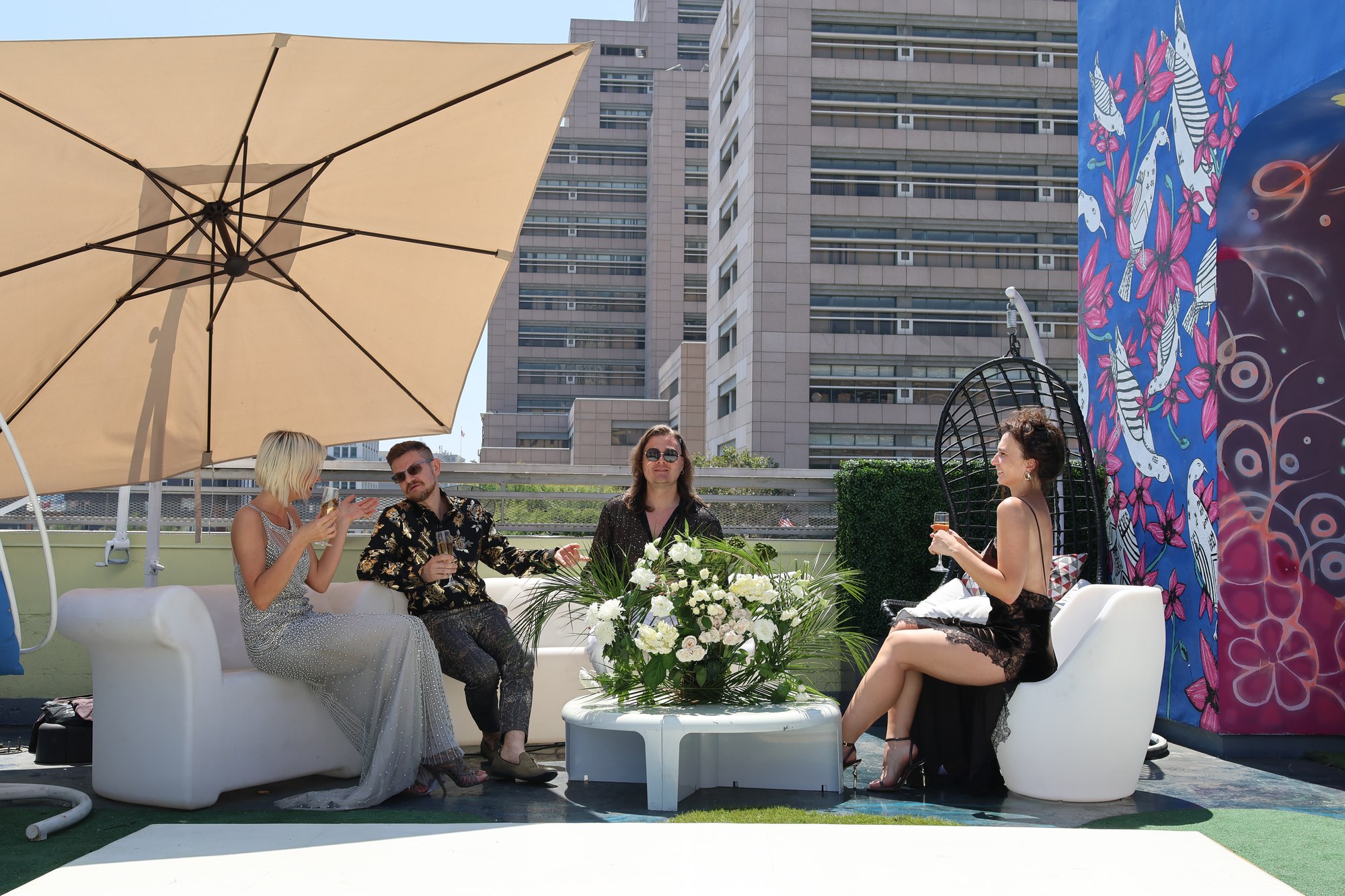 Guests with champagne in rooftop lounge seating beside a painted mural
